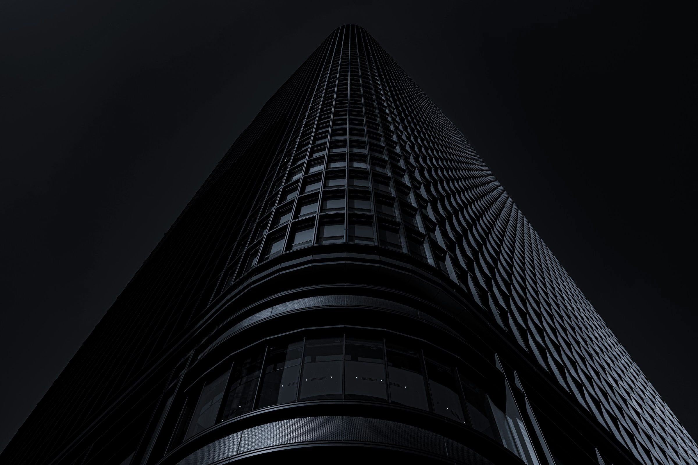 A dark glass tower seen from below against a night sky
